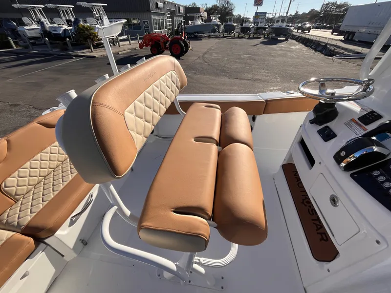 Slide: The Image of 2025 NauticStar 242L Offshore boat interior with tan cushioned seating and steering console. - 8