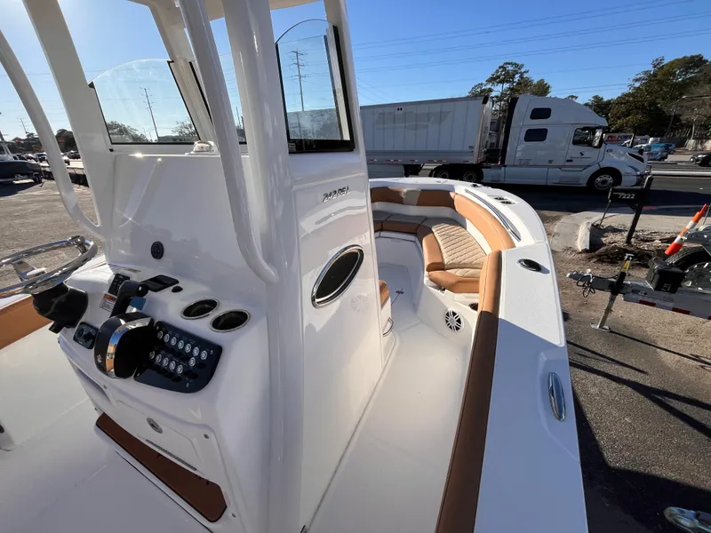 Slide: The Image of 2025 NauticStar 242L Offshore boat interior with console and seating, parked outdoors. - 9