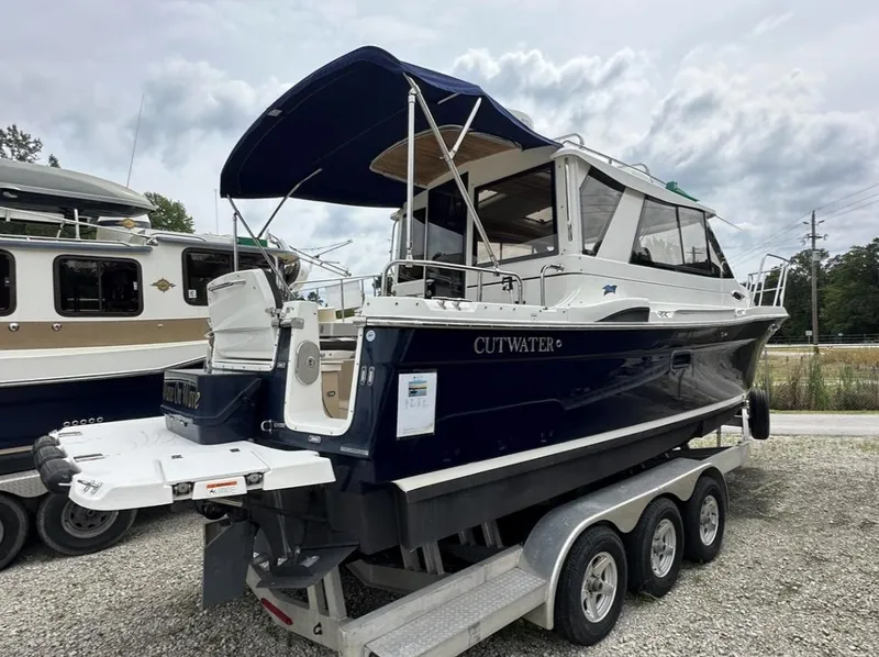 Slide: The Image of 2016 Cutwater C-26 boat on a trailer, featuring a dark blue hull and covered cockpit. - 2