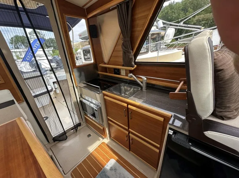 Slide: The Image of Interior of a 2016 Cutwater C-26 boat featuring a compact kitchen area. - 21