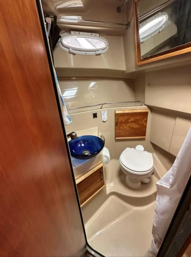Slide: The Image of 2016 Cutwater C-26 boat bathroom with blue sink, toilet, and wooden cabinets. - 27