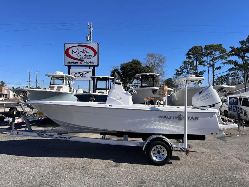 The Image of 2025 NauticStar 194 Bay boat on trailer at dealership, clear sky background. - 0