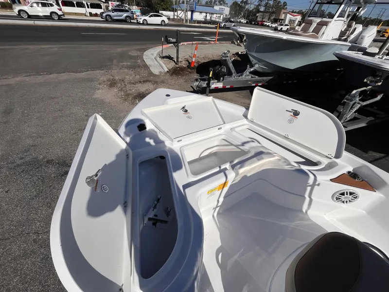 Slide: The Image of 2025 NauticStar 194 Bay boat with open storage compartments, parked on a street. - 10