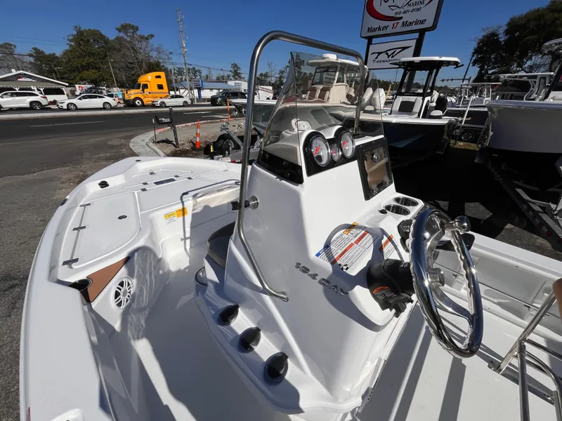 Slide: The Image of 2025 NauticStar 194 Bay boat interior with steering wheel and dashboard, parked outdoors. - 13