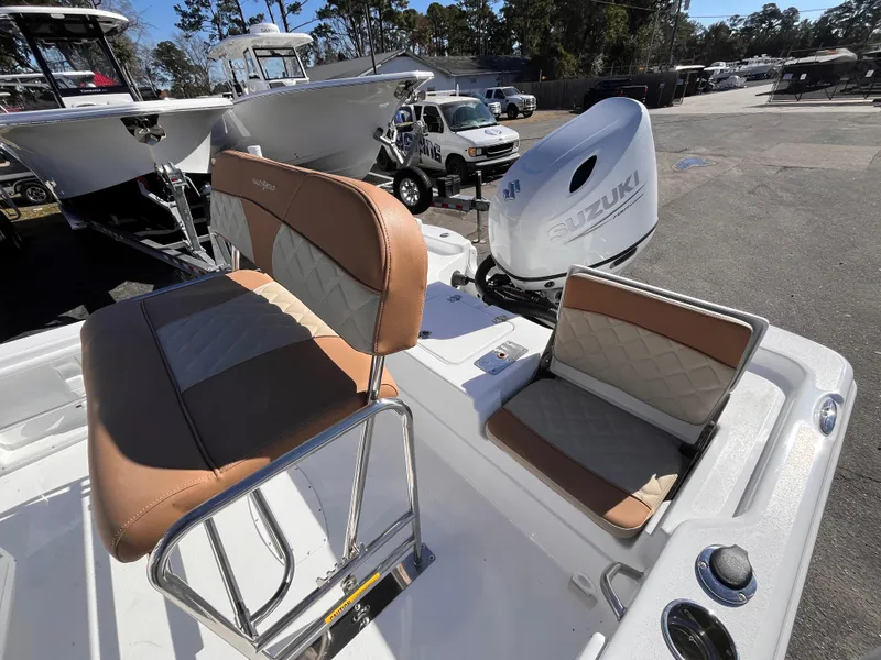 Slide: The Image of 2025 NauticStar 194 Bay boat interior with Suzuki outboard motor, featuring tan and gray seating. - 14
