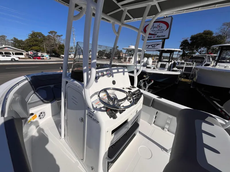 Slide: The Image of 2025 NauticStar 212 Legacy boat interior with steering console and seating, displayed outdoors. - 12