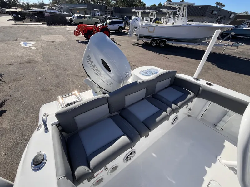 Slide: The Image of 2025 NauticStar 212 Legacy boat with cushioned seating and outboard motor in a marina. - 5