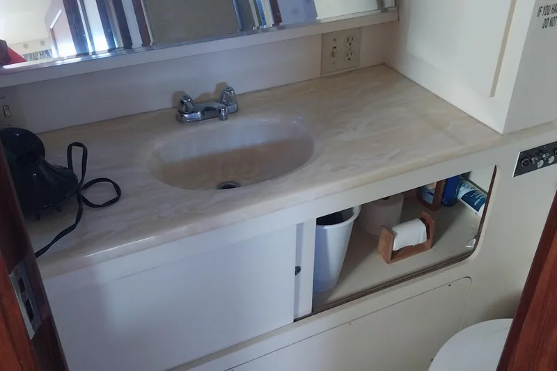 Slide: The Image of Bathroom sink area in 1988 Hatteras 40 Double Cabin yacht, featuring storage and mirror. - 20