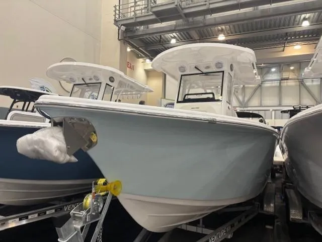 The Image of 2025 Sea Pro 242 Center Console boat on trailer, dockside under clear blue sky. - 0