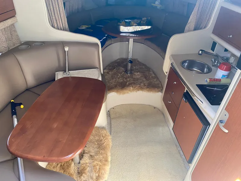 Slide: The Image of 2003 Chaparral Signature 280 cabin interior with seating, table, kitchenette, and cozy decor. - 18