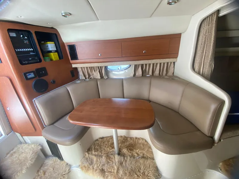 Slide: The Image of 2003 Chaparral Signature 280 interior with curved seating, wooden table, and storage cabinets. - 19