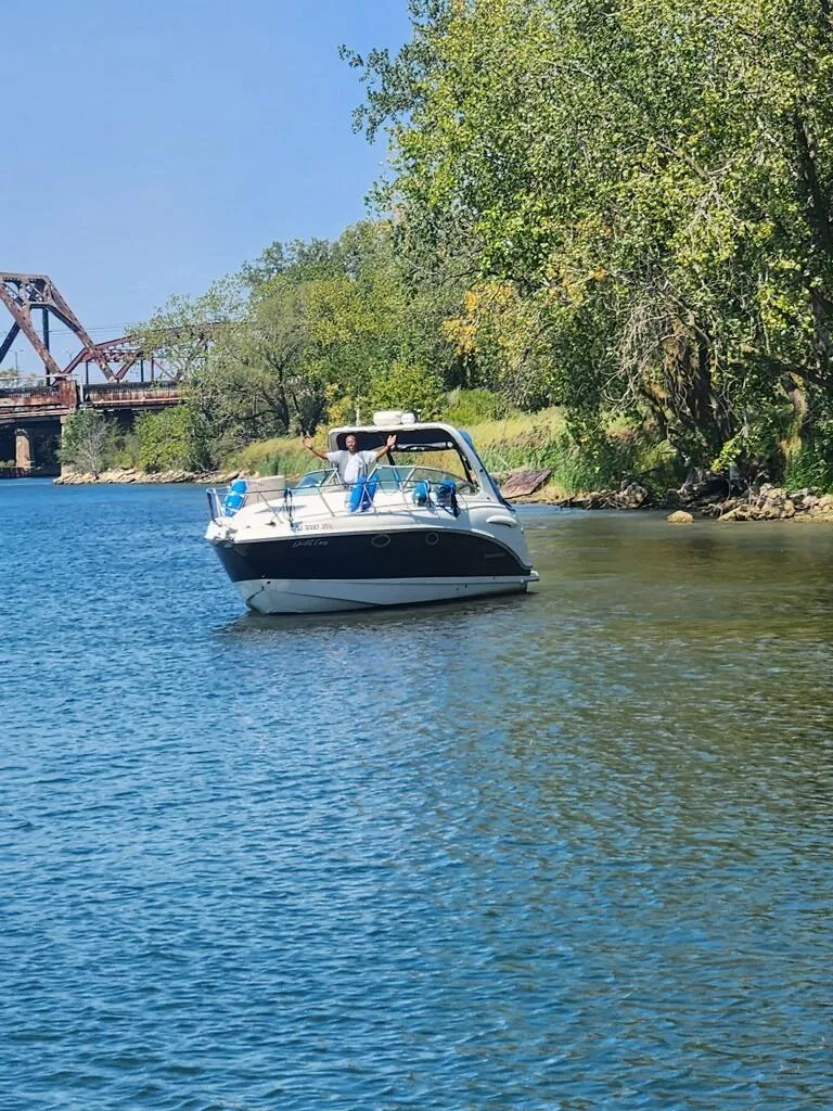 Slide: The Image of 2003 Chaparral Signature 280 boat cruising on a scenic river near a bridge and lush greenery. - 8