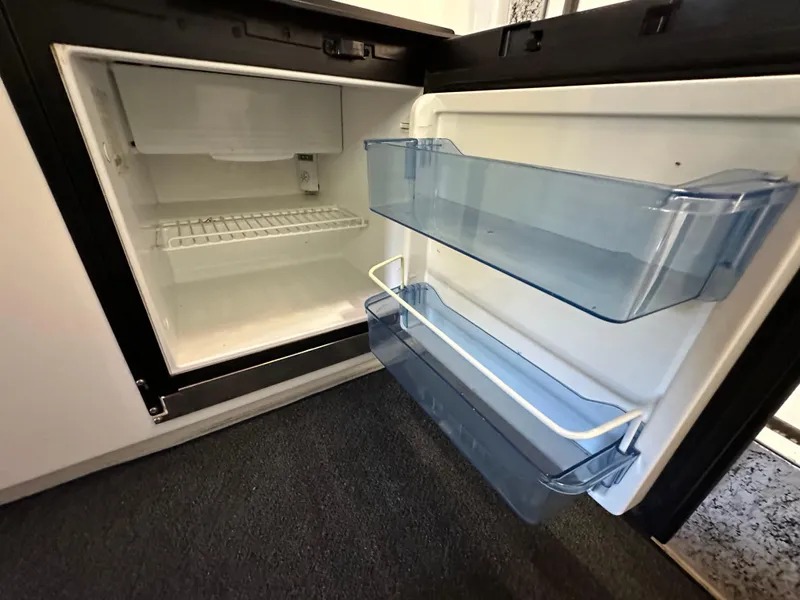 Slide: The Image of Open refrigerator in a 2005 Farallon 28 boat, showing empty shelves and door compartments. - 40