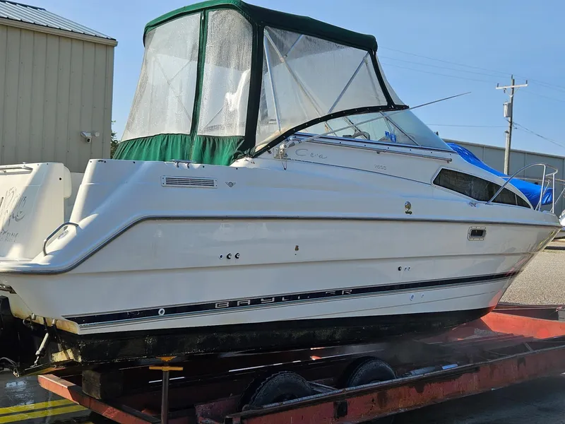 The Image of 1997 Bayliner 26 Cierra boat on trailer, white with green canopy, parked outdoors. - 0