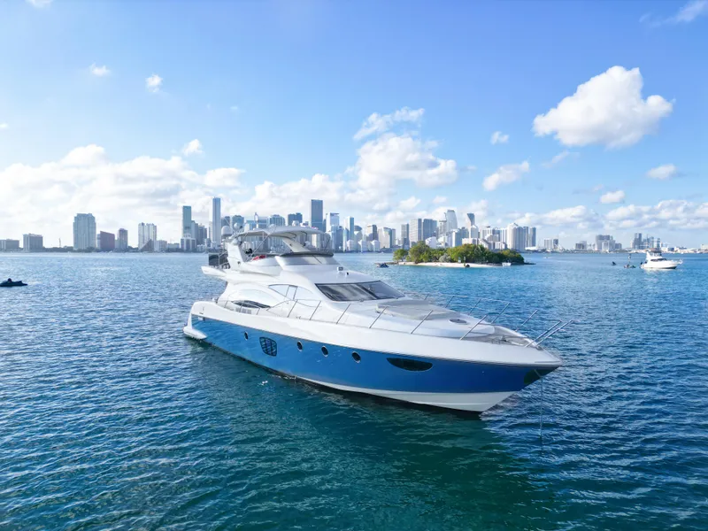 Slide: The Image of 2007 Azimut 68E yacht cruising in sunny waters with city skyline backdrop. - 1