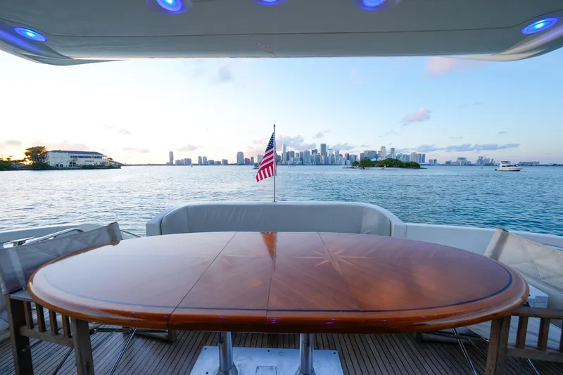 Slide: The Image of Azimut 68E 2007 yacht deck with wooden table, overlooking city skyline and water. - 22