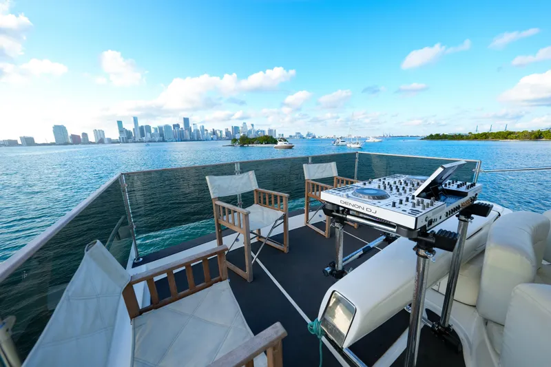 Slide: The Image of Azimut 68E yacht deck with DJ setup, overlooking city skyline and ocean, 2007 model. - 25