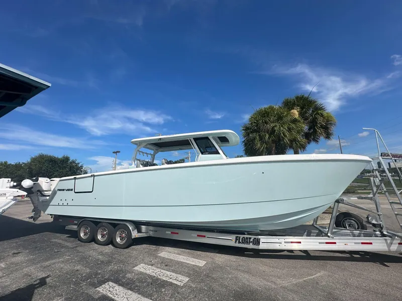 Slide: The Image of 2025 Twin Vee 400 GFX2 CC boat on trailer under clear blue sky. - 2