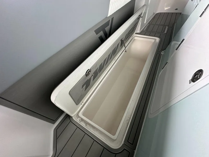 Slide: The Image of 2025 Twin Vee 400 GFX2 CC boat storage compartment, open lid, sleek design. - 31