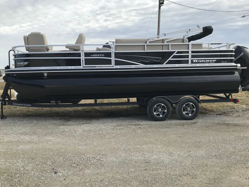 Slide: The Image of 2025 Ranger Reata 223FC pontoon boat on trailer, parked outdoors. - 2