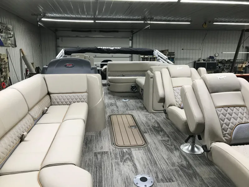 Slide: The Image of 2025 Ranger Reata 223FC pontoon boat with beige seating in a garage setting. - 9