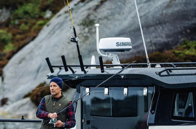 Slide: The Image of Man fishing on Navan C30 boat, 2025 model, near rocky shoreline. - 2