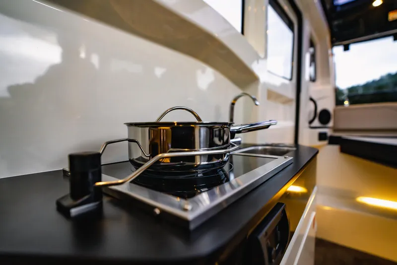 Slide: The Image of Modern kitchen inside 2025 Navan C30, featuring sleek stovetop and stainless steel pot. - 9