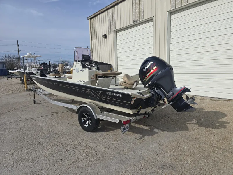 Slide: The Image of 2019 Xpress H20B boat with Yamaha outboard motor on trailer, parked outside a building. - 3