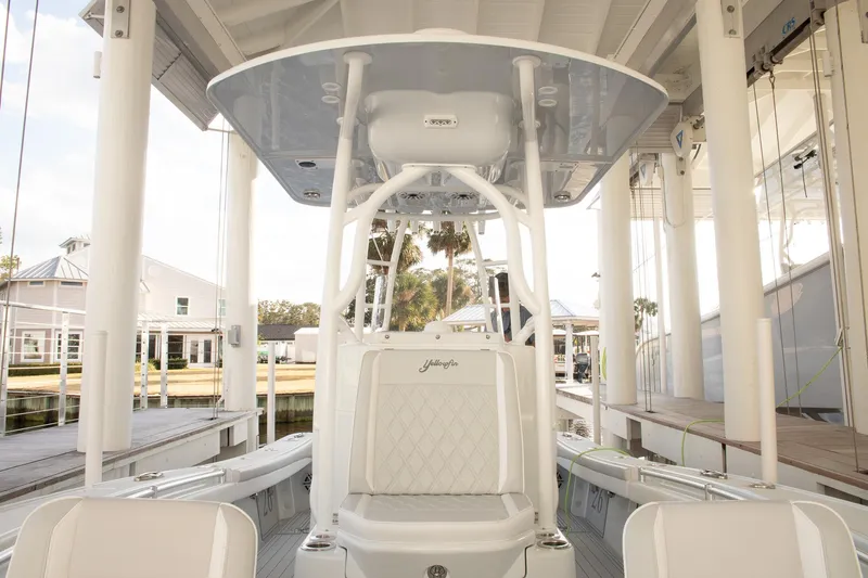 Slide: The Image of 2023 Yellowfin 26 Hybrid boat interior with white seating and T-top in marina. - 29