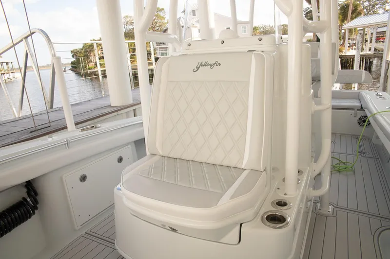 Slide: The Image of 2023 Yellowfin 26 Hybrid boat interior with cushioned seating and cup holders. - 30