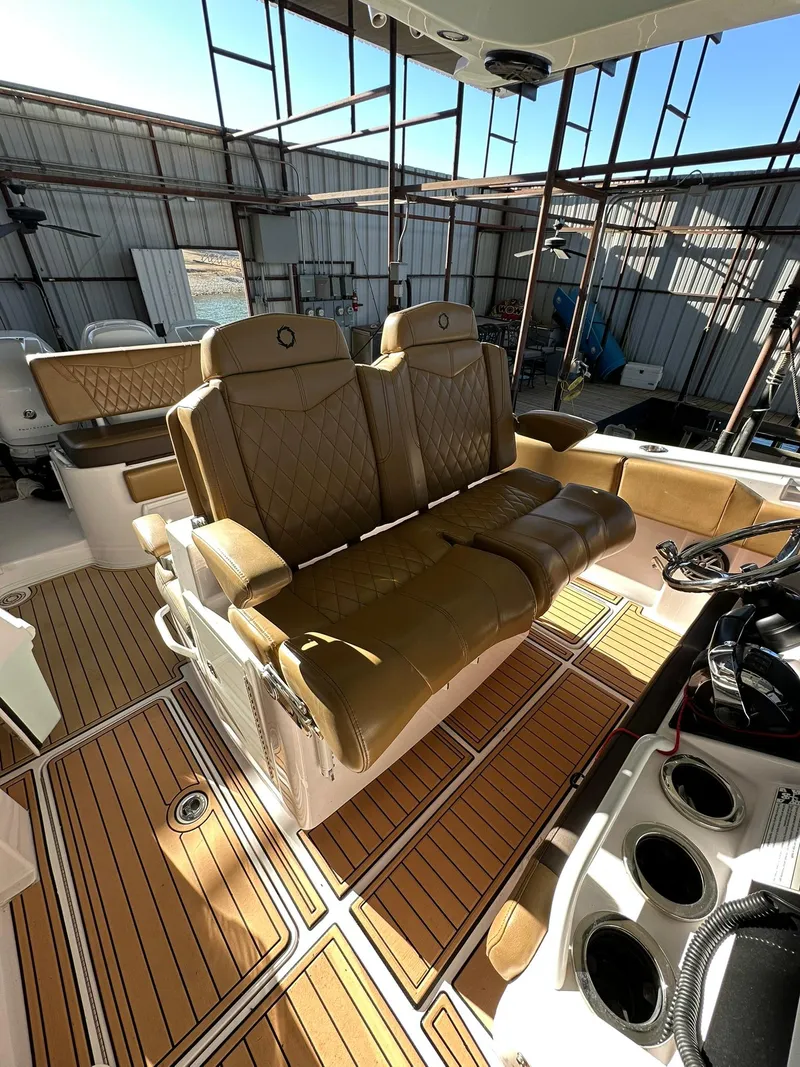 Slide: The Image of 2018 Fountain 38 CC boat interior with tan leather seats and wood-patterned flooring. - 11