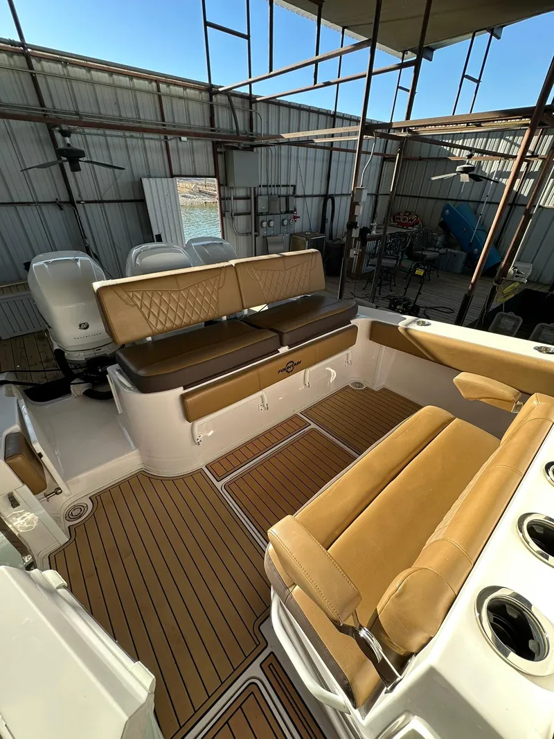 Slide: The Image of 2018 Fountain 38 CC boat interior with tan seating and wood flooring in a covered dock. - 12
