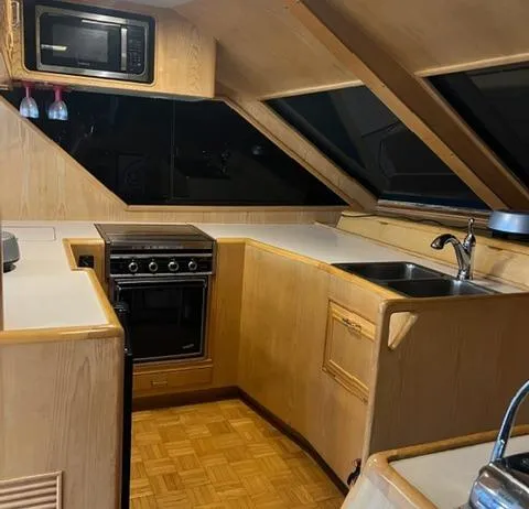 Slide: The Image of 1989 Ocean Alexander 42 yacht kitchen with wood cabinetry, stove, microwave, and sink. - 29