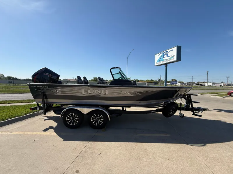 Slide: The Image of 2025 Lund 2075 IMPACT XS boat on trailer in parking lot, sunny day. - 0