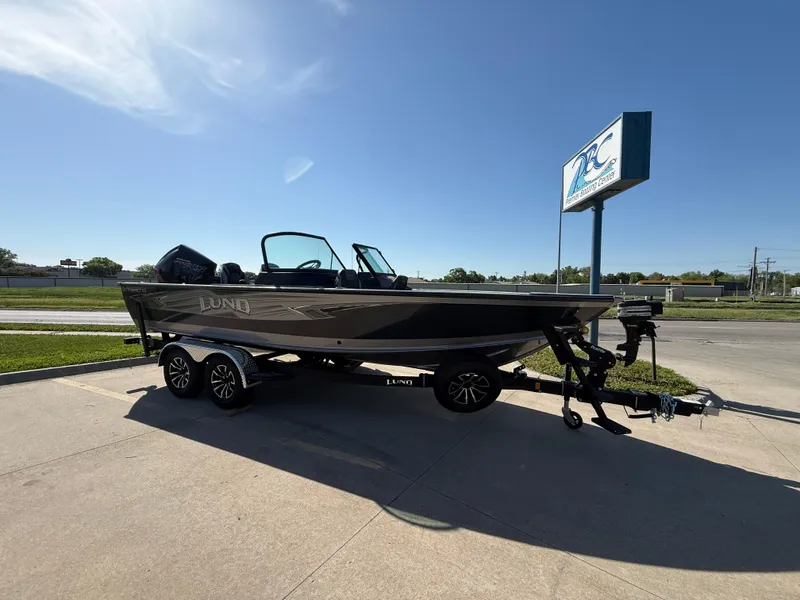 Slide: The Image of 2025 Lund 2075 IMPACT XS boat on trailer, parked outdoors under clear blue sky. - 1