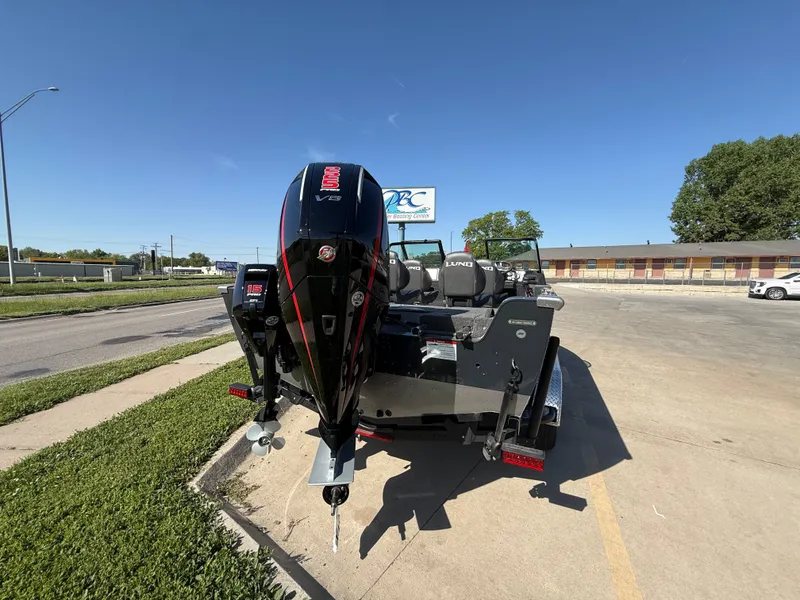 Slide: The Image of 2025 Lund 2075 IMPACT XS boat with outboard motor, parked on a sunny day. - 4