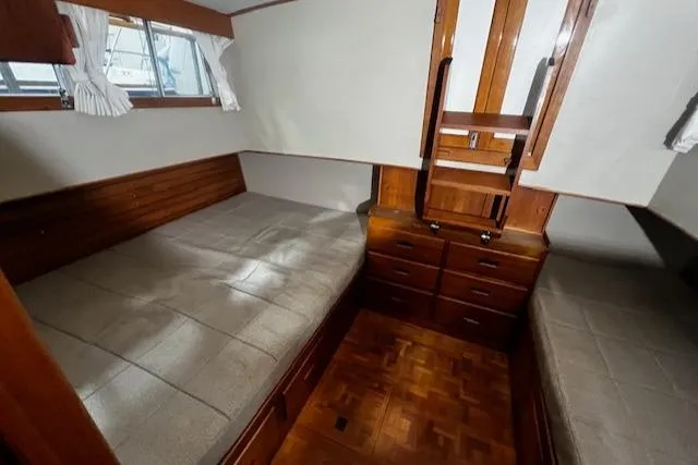 Slide: The Image of 1984 Grand Banks Trawler cabin with twin beds, wooden interior, and storage drawers. - 12
