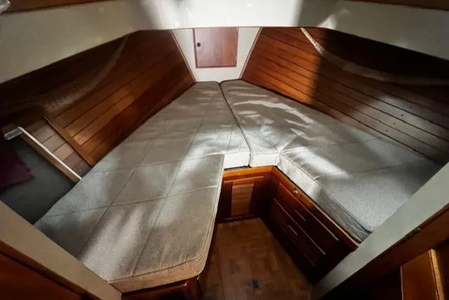 Slide: The Image of 1984 Grand Banks Trawler cabin with wooden interior and cushioned V-berth. - 13