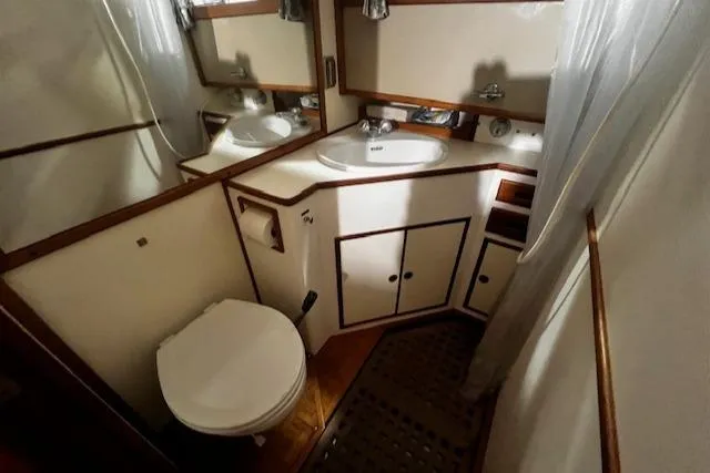 Slide: The Image of 1984 Grand Banks Trawler bathroom with sink, toilet, and wooden cabinetry. - 17