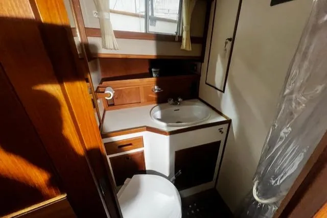Slide: The Image of 1984 Grand Banks Trawler bathroom with sink, toilet, and wooden cabinetry. - 18