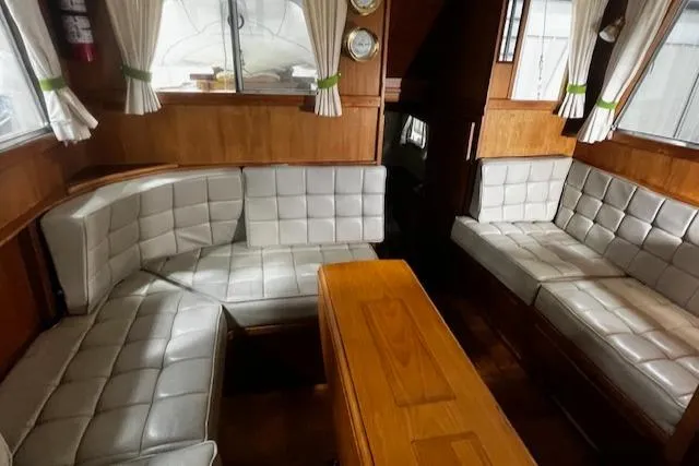 Slide: The Image of 1984 Grand Banks Trawler interior with cushioned seating and wooden table. - 2