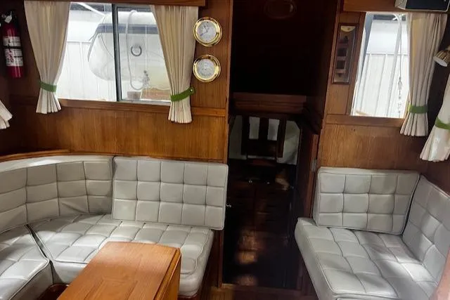 Slide: The Image of 1984 Grand Banks Trawler interior with white cushioned seating and wooden accents. - 3