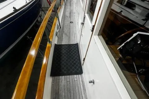 Slide: The Image of 1984 Grand Banks Trawler deck with wooden railings and black mat. - 30