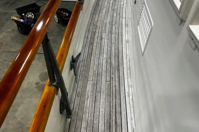 Slide: The Image of 1984 Grand Banks Trawler deck with wooden flooring and polished railings. - 32