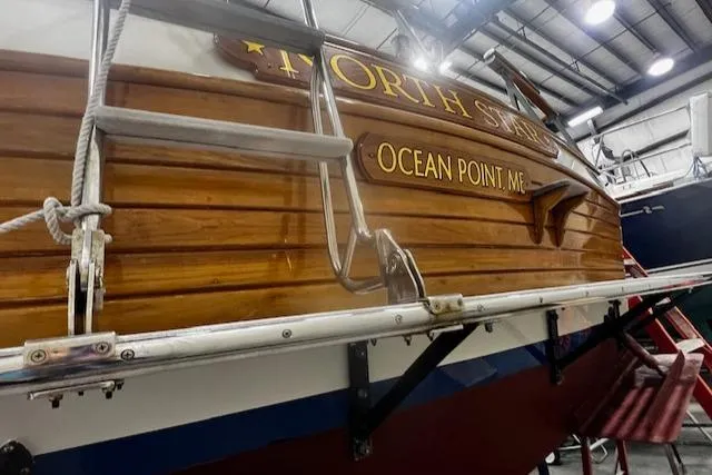 Slide: The Image of 1984 Grand Banks Trawler in a boatyard, featuring wooden hull and ladder. - 39