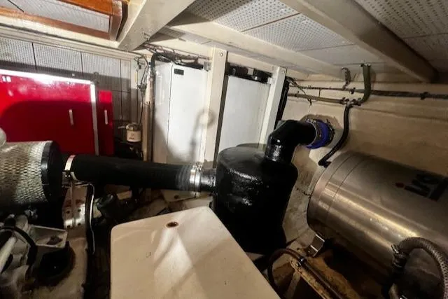 Slide: The Image of Engine room of a 1984 Grand Banks Trawler, featuring pipes and mechanical components. - 49