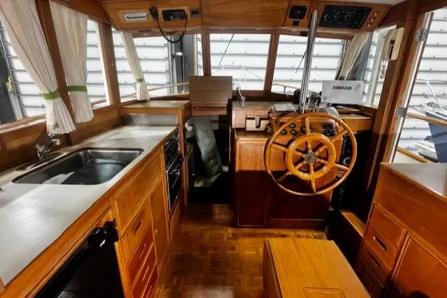 Slide: The Image of 1984 Grand Banks Trawler interior with wooden helm, kitchen, and navigation equipment. - 5