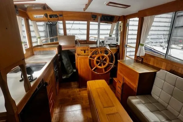 Slide: The Image of 1984 Grand Banks Trawler interior with wooden helm, seating, and kitchen area. - 6