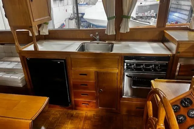 Slide: The Image of 1984 Grand Banks Trawler kitchen with wood cabinetry, sink, stove, and refrigerator. - 7