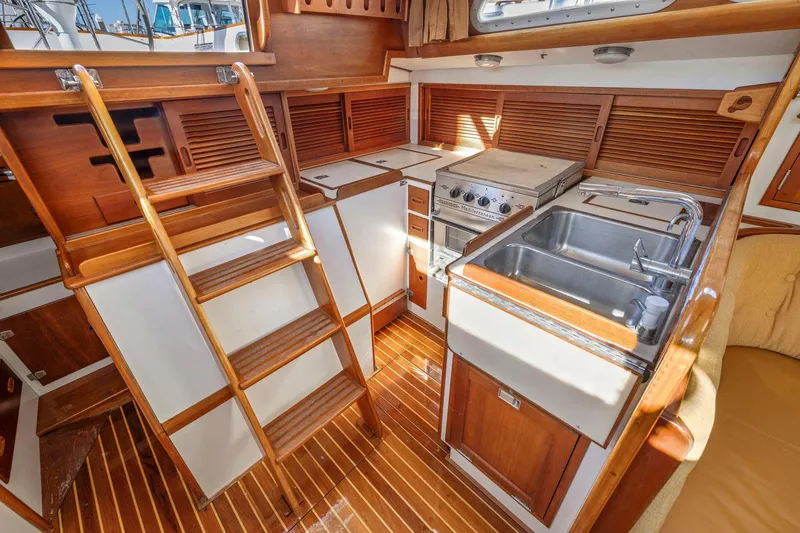 Slide: The Image of 1987 Hinckley Sou'wester 42 yacht interior with wooden cabinetry and compact kitchen area. - 31